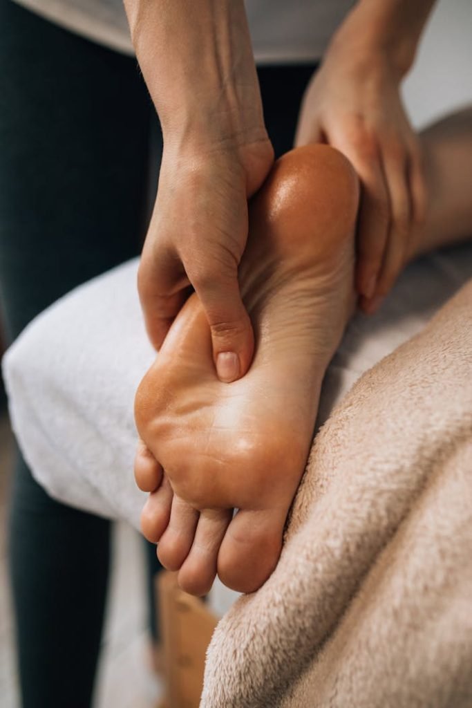a-person-having-a-foot-massage-6628700 Hands massaging a foot to provide relaxation and promote wellness indoors.